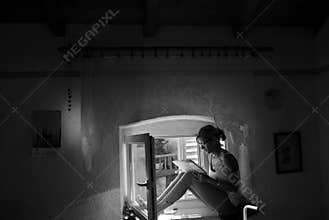 The writer re-reading her notes sitting on the window