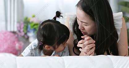 Young Asian Mother and child kissing and hugging, Resting on bed together