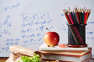 Back to School concept, school supplies, biscuits, packed lunch and lunchbox over white chalkboard, selective focus.