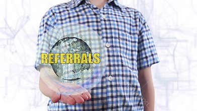 Young man shows a hologram of the planet Earth and text Referrals