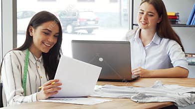 Female fashion designer showing her sketches to a colleague