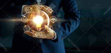 Businessman holding glowing light bulb with energy sources icon