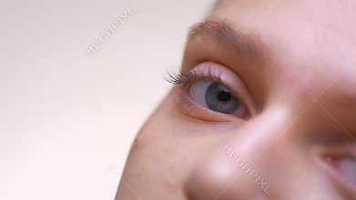 Open calm sight straight at camera close-up, crear skin of caucasian female with beautiful blue eyes in white studio