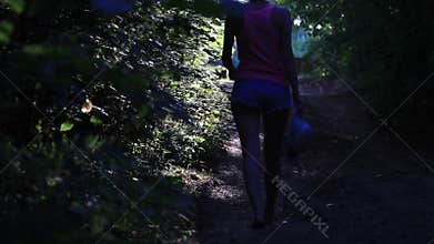 Young female walking in the forest away from the camera