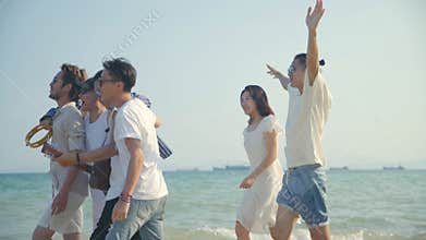 Young asian adults men and women having fun walking singing on beach