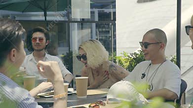 Young asian adults men and woman sitting at an outdoor coffee place talking chatting laughing