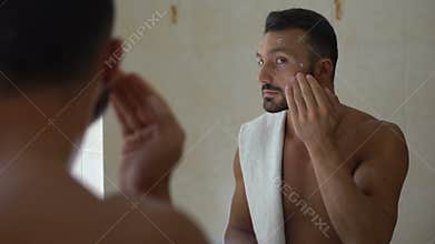 Metrosexual applying moisturizing lotion and massaging face, body care cosmetics