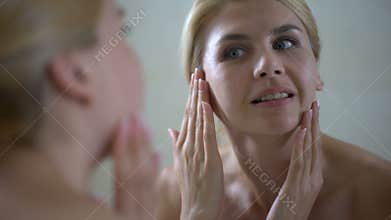 Middle aged woman satisfied with face condition after beauty therapist visit