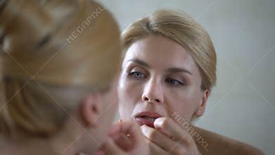 Insecure pretty lady popping pimple on skin, scrutinizing her mirror reflection