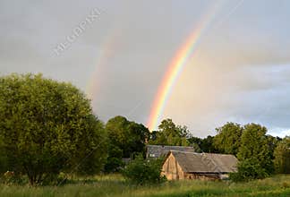 Double rainbow over the forest and houses at countryside.