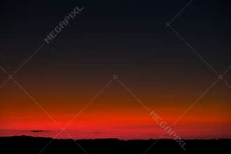 Sunset sky with bright red horizon and crescent moon