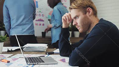 Pensive male office worker looking at computer screen with data
