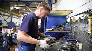 Side view technician checks and assembles truck part
