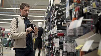 Man is holding in hands a sport roller simulator, standing in hall of shop