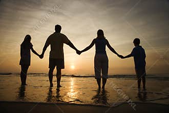 Family Holding Hands on Beach Watching the Sunset