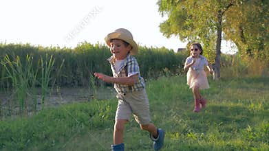 Cheerful kids running around outdoors in countryside during a happy summer holiday in backlight