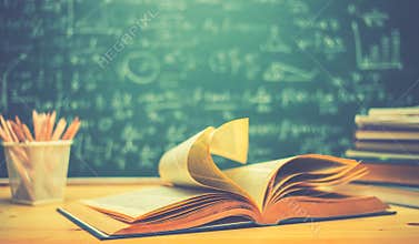 School books on desk formulas and Physics inscription on the blackboard , education concept