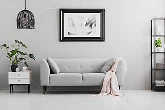Poster above grey sofa with pink blanket in living room interior