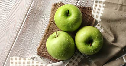 Wet green apples on canvas
