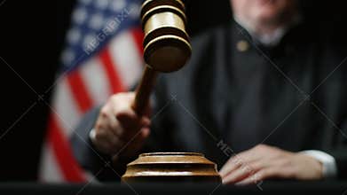 Judge with wooden hammer in his hand against American flag in USA court room