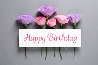 Flat lay composition of Eustoma flowers and card with greeting HAPPY BIRTHDAY