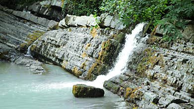 Scenic nature of a beautiful waterfall and emerald of a fresh water lake in a wild jungle forest environment. 4k, slow