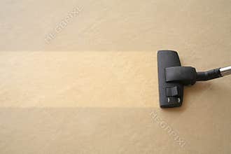 A vacuum cleaner is cleaning the carpet ground, like lawn mower cutting a grass surface, making an even color surface, place for