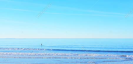 Calm blue sea ocean water landscape with surfer standing on surf board