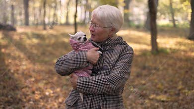 Senior woman kissing her dog pet in park