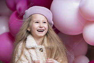 Laughing little girl in beret playing with pink, purple balloons.   child on holiday