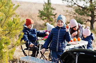 Cheerful mother with kids at a picnic. Family on vacation with fruits outdoor
