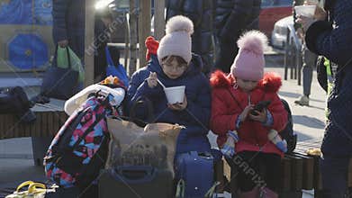 Lviv, Ukraine - March 15, 2022: Child sitting on the railway station and eating at the street during the evacuation from