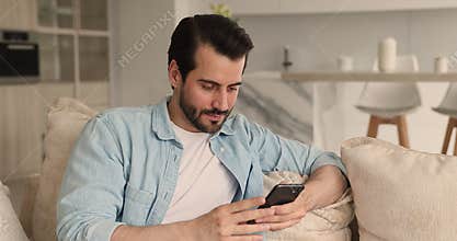 Happy focused 30s man using smartphone in hands.