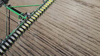 Farmer on tractor with seeding machinery driving over field sows seeds or grain of wheat or corn. Agricultural
