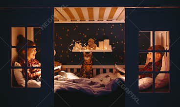 Happy kids reading books on bed at night