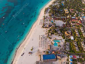 Aerial view of Thatched Roof Umbrellas Pattern on Wide Coastal line of White Sand of Kendwa Beach in Kendwa village