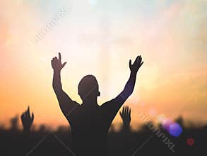 Silhouette of Crowd Raising Hands in Worship against Vibrant Sunset Sky with Lens Flare