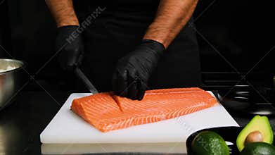 Cutting Salmon fillet in large pieces. Chef cutting Salmon on to big pieces on white desk.