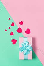 Pink gift box with blue bow on pastel two-color background pink and mint, copy space, flat lay. March 8, February 14, birthday, St