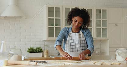 African woman wear apron rolls out the dough for baking
