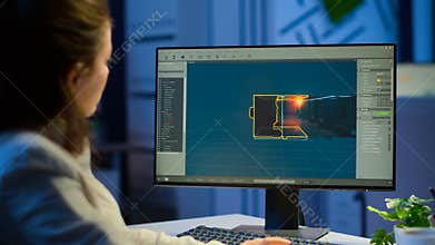 Woman game designer looking at computer screen working late night