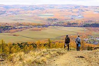 two mature tourists at the top of the ridge admire the Ural mountains and taiga