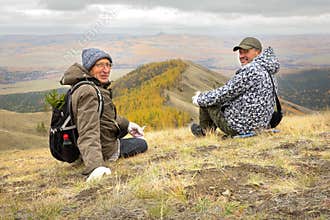 two mature tourists at the top of the ridge admire the Ural mountains and taiga