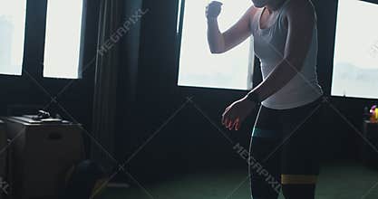 Beautiful young athletic blonde woman gets up exhausted after working out with professional male coach at modern gym.