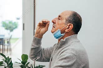 Senior man using an nasal swab for covid 19 detection