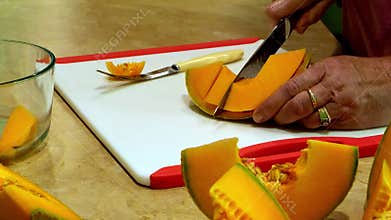 Cantaloupe muskmelon wedges are cut into sections with two knives.