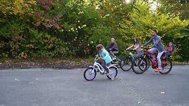 Family biking in park in bright sunshine