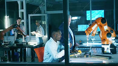 Engineers grasping tricks of smart manufacturing using industrial robots. Team of industrial robotics engineers working