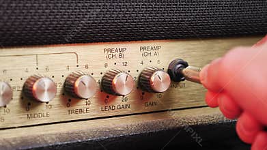 Hand is plugging jack cable into music guitar amplifier, close up. Hand pluges guitar cable in vintage amplifier. Music concept. S