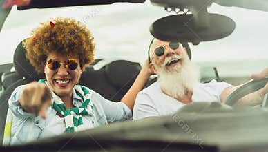 Happy senior couple having fun driving on new convertible car - Mature people enjoying time together during road trip